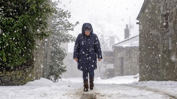 Una mujer camina por una calle nevada de O Cebreiro.