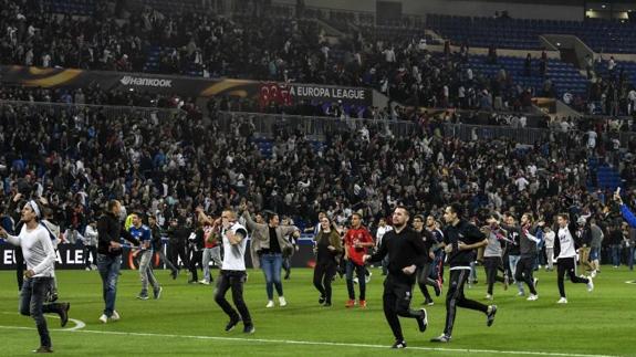 Aficionados del Lyon, sobre el césped del estadio tras ser agredidos. 