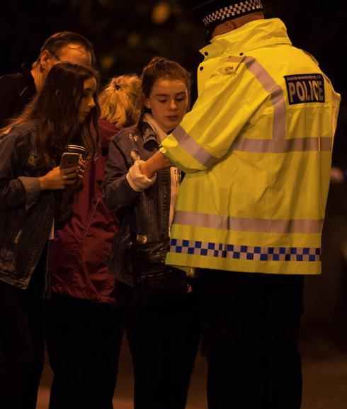 Asistentes al concierto hablan con un policía.