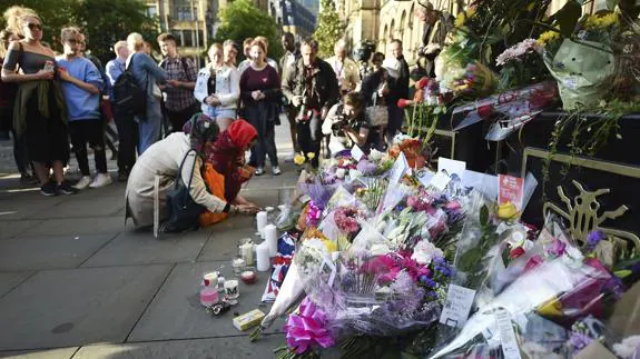 Varias personas dejan flores durante una vigilia por las víctimas del atentado en Mánchester.