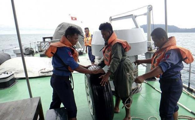 Miembros de la Armada birmana recuperan del mar de Andamán una de las ruedas del avión siniestrado.