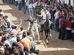 El público se agolpa peligrosamente a ambos lados de la corredera por la que cabalgan a gran velocidad los jinetes. / M.NÚÑEZ