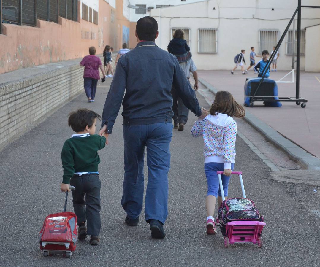 Un padre acompaña a sus hijos al colegio.