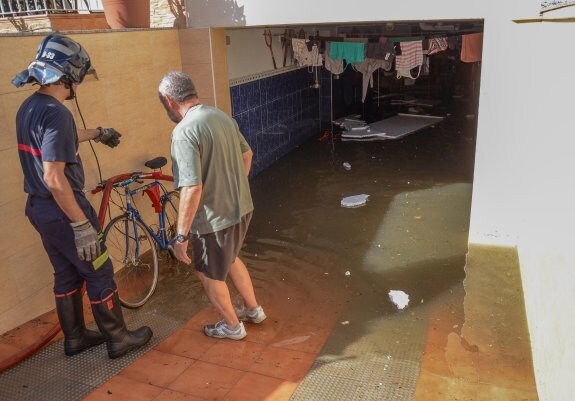 Un bombero habla con un vecino cuyo garaje ha quedado anegado. :: c. moreno