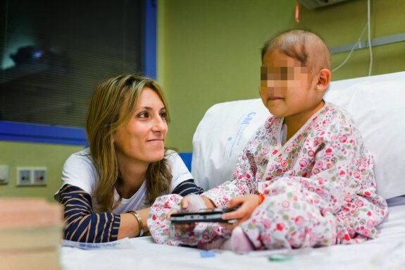 Mónica Esteban, con una niña enferma a la que su fundación le ha regalado una consola. :: v. izquierdo