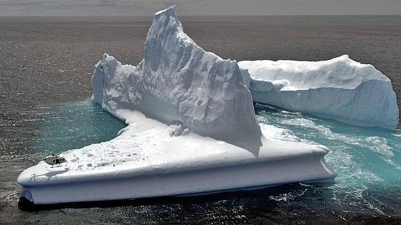 Helicóptero (parte inferior, izda) sobrevuela a baja altura un iceberg que flota arrastrada por la corriente por las aguas de Dunedin (Nueva Zelanda) HOY