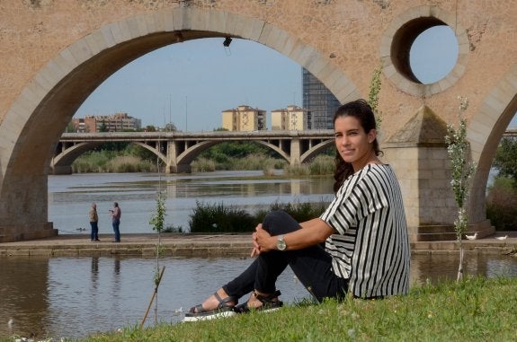 Miriam Casillas, que ha pasado esta semana de descanso en Badajoz, posa en el parque del río con el Puente de Palmas detrás. :: C. MORENO