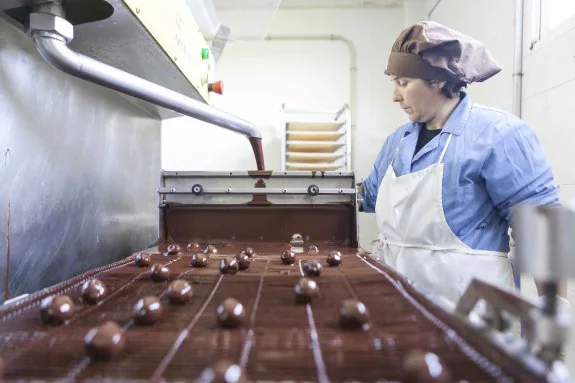 Una empleada de la fábrica de Valdefuentes controla el proceso de bañado de chocolate de cerezas. 