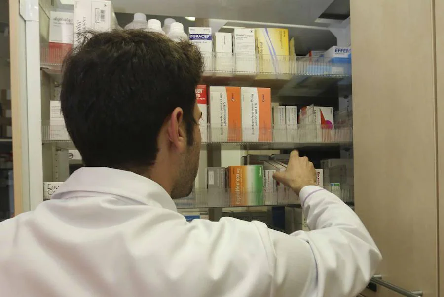 Un empleado de una farmacia extremeña busca un medicamento en los estantes