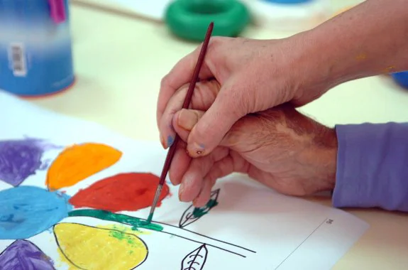 Una cuidadora ayuda a un anciano a realizar un dibujo en un centro público de la región. :: hoy