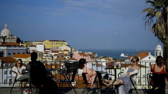 Turistas disfrutan de una terraza en el mirador del barrio de Alfama, en Lisboa