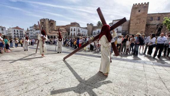 Penitentes de la Sagrada Cena descalzos llevando una cruz durante la procesión 