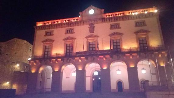 Ayuntamiento de Cáceres, iluminado de color naranja.