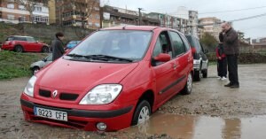 Un coche se quedó atrapado ayer en uno de los socavones que la lluvia ha creado en el aparcamiento de tierra de las huertas de la Isla. ::                             ANDY SOLÉ