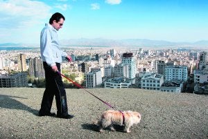 Un hombre pasea a su perro por Tochal,                         con Teherán al fondo. ::                             HASAN SARBAKHSHIAN/AP