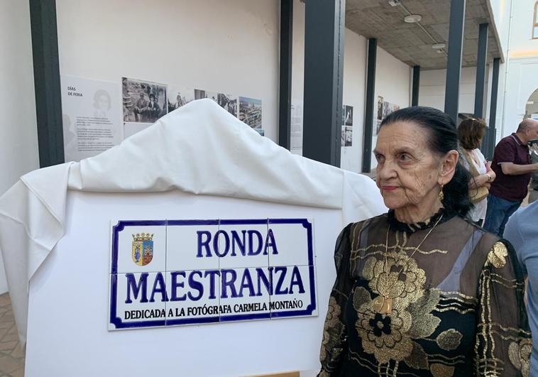 La homenajeada junto a la placa de la calle dedicada y ante la exposción