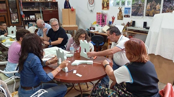 Jóvenes y adultos aprenden el arte de elaborar piezas belenistas en un taller