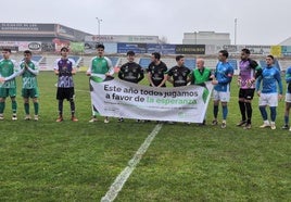 Los jugadores con la pancarta de la AECC antes del partido