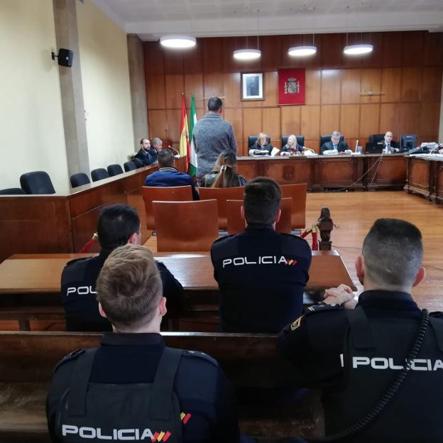 Agentes custodiando a los acusados en la sala. 