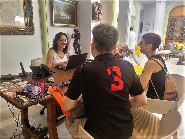 Turistas en el hotel Oleum son atendidas por la recepcionista.