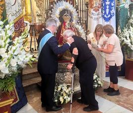 Manuel José Gómez, ayuda a un mayor a besar a la Virgen.