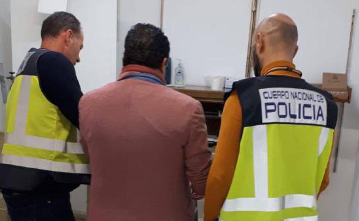 Dos agentes policiales con uno de los detenidos durante la operación. 