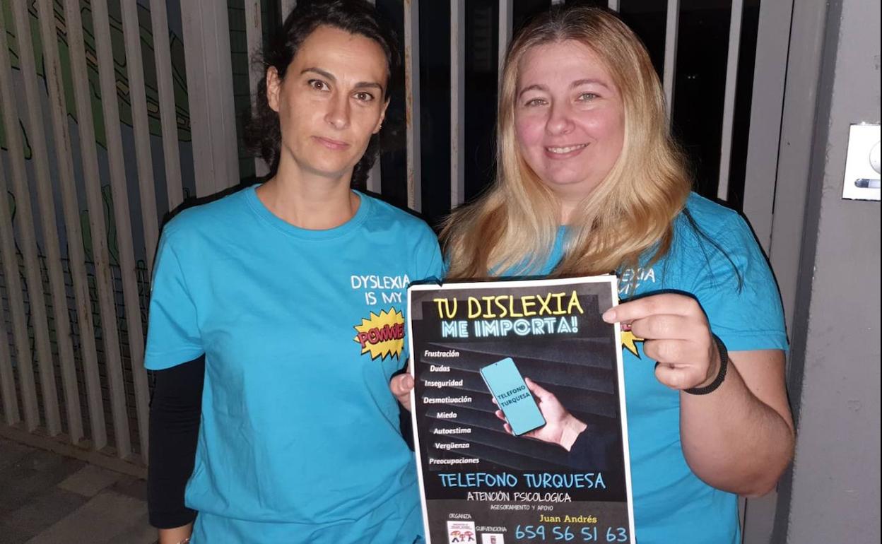 Agustina Quiñonero e Isabel Romero con el cartel del nuevo teléfono turquesa. 