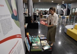 Una mujer ve una portada de un libro en una biblioteca de El Ejido.