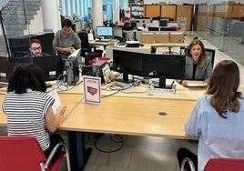 Varias personas trabajan con ordenadores en una oficina.