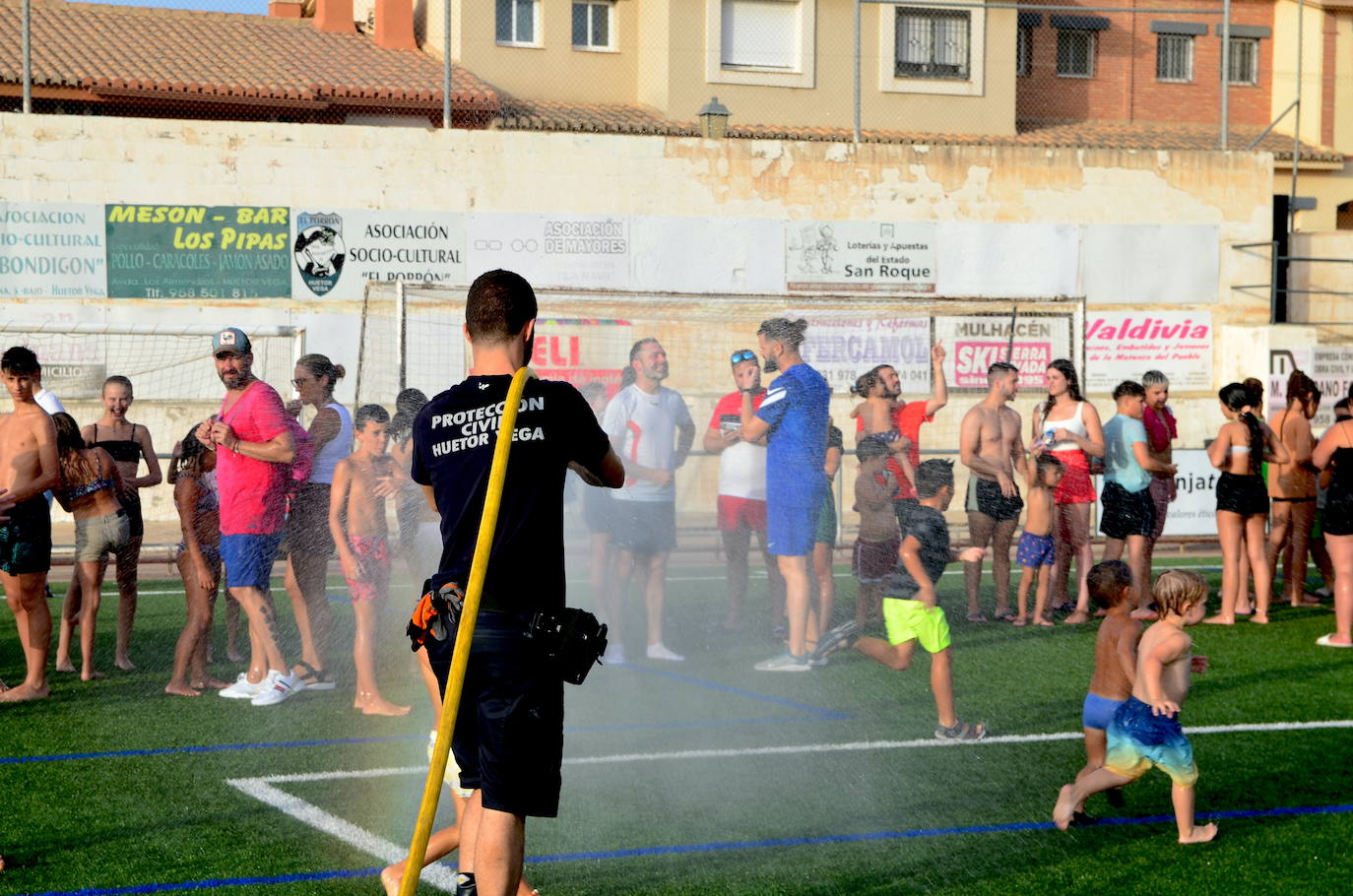 Un voluntario de Protección Civil de Huétor Vega da juego refrescando con una manguera.