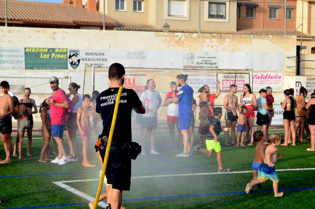 Un voluntario de Protección Civil de Huétor Vega da juego refrescando con una manguera.