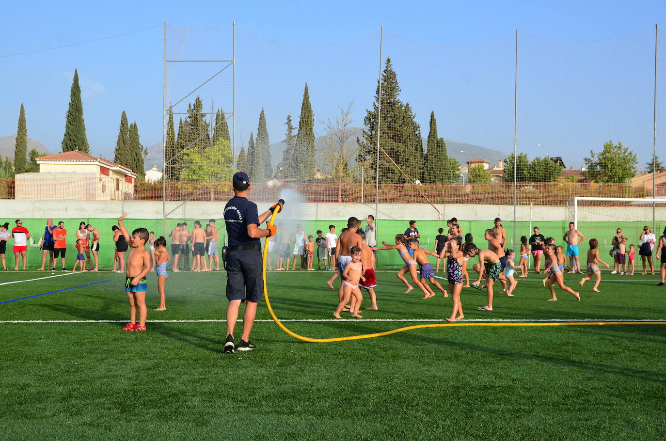 Un voluntario de Protección Civil de Huétor Vega da juego refrescando con una manguera.
