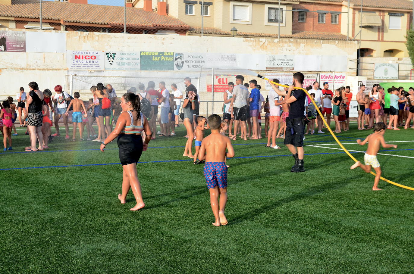 Un voluntario de Protección Civil de Huétor Vega da juego refrescando con una manguera.
