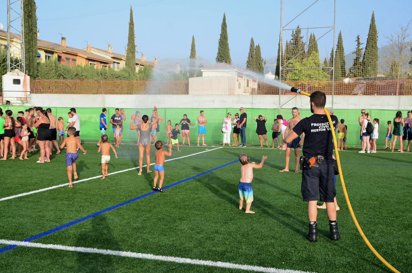 Un voluntario de Protección Civil de Huétor Vega da juego refrescando con una manguera.