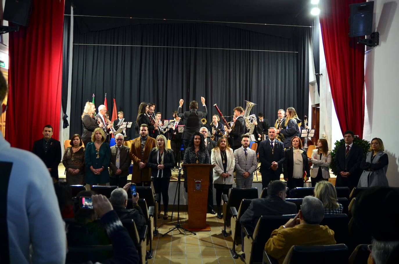 Miembros de la corporación municipal entonan el himno de Andalucía junto a la Banda de Música de Huétor Vega.