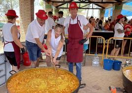 El alcalde y la concejala de Fiestas remueven el arroz.