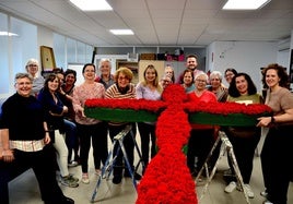 Las mujeres participantes en el taller de croché creativo del 8M en Huétor Vega adornan la cruz municipal con claveles de ganchillo.