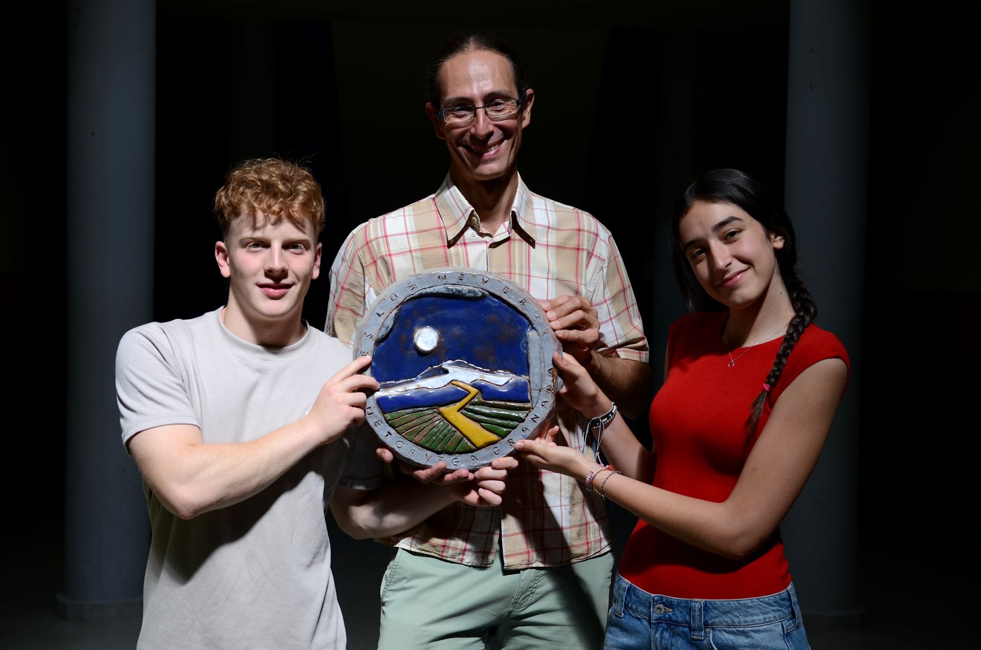 Sergio Burrell Gámiz y Aitana Cecilia Masmano Martínez sujetan el escudo del IES Los Neveros con José Cabrera Martos, jefe de Formación, Evacuación e Innovación Educativa.