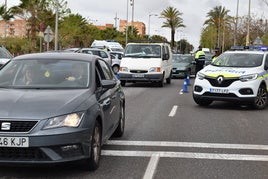 Varios vehículos pasan por una carretera de Vícar, bajo la atenta mirada de agentes de la Policía Local.