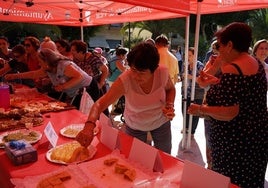 Una vecina cogiendo un pincho de tortilla en un evento de la localidad.