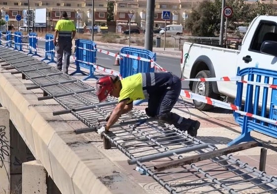 Un trabajador se encarga de reparar una de las vallas metálicas.