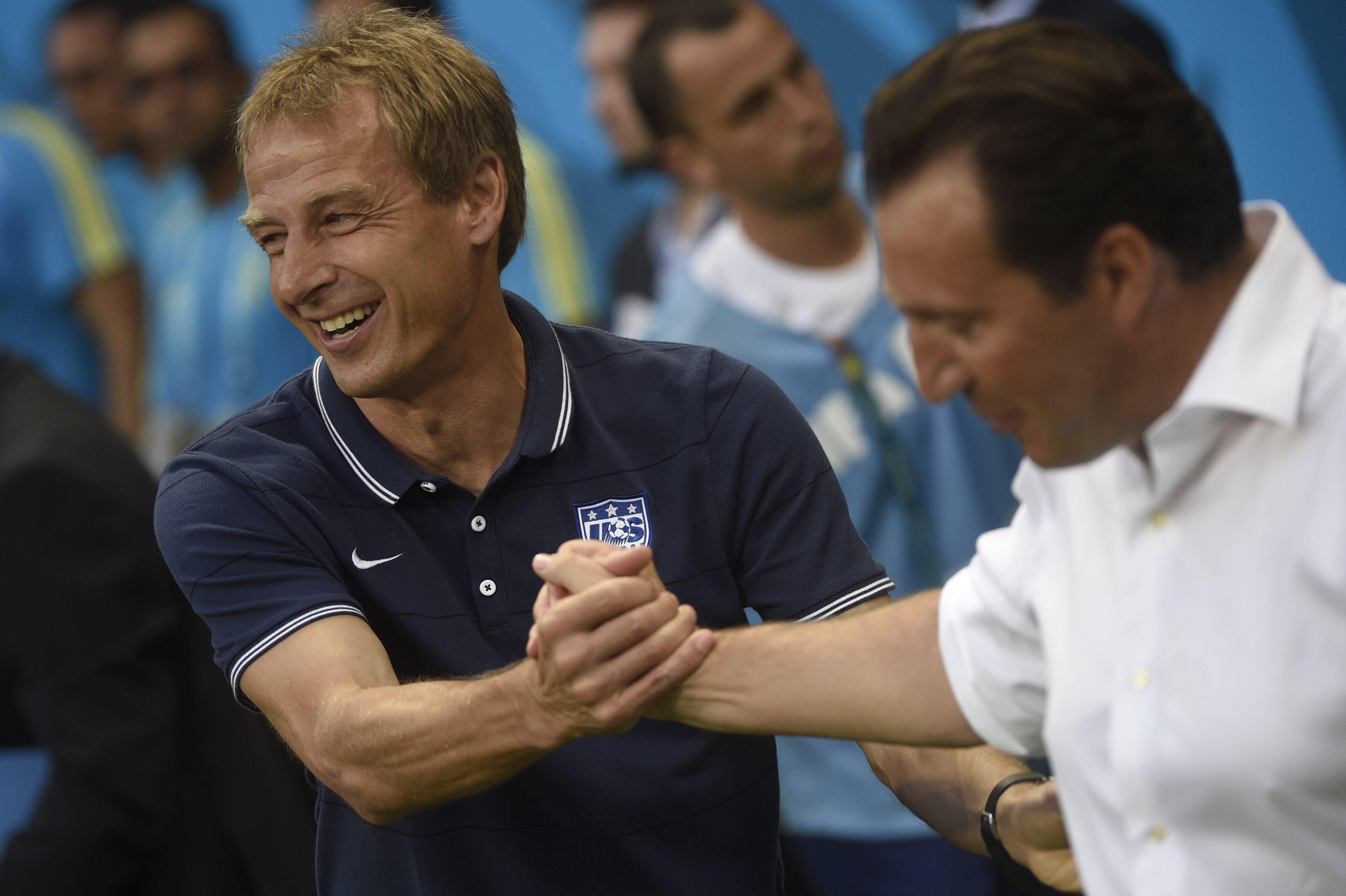 Jürgen Klinsmann (i) y Marc Wilmots (d), técnicos de Estados Unidos y Bélgica, se saludan antes del partido.