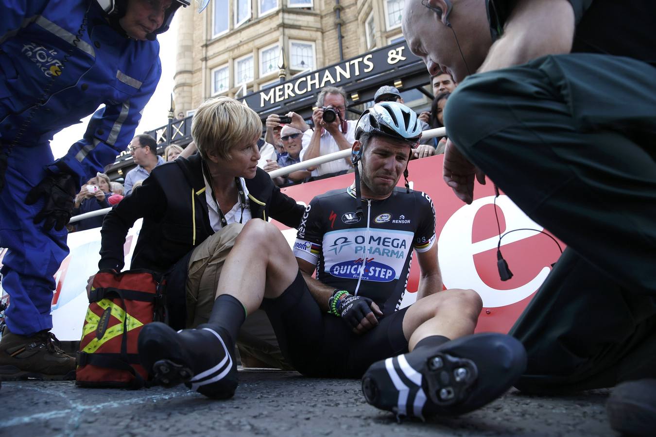 El ciclista Mark Cavendish recibe ayuda después de estrellarse durante un sprint masivo al lado de la línea de llegada de la primera etapa del Tour de Francia de Leeds a Harrogate.