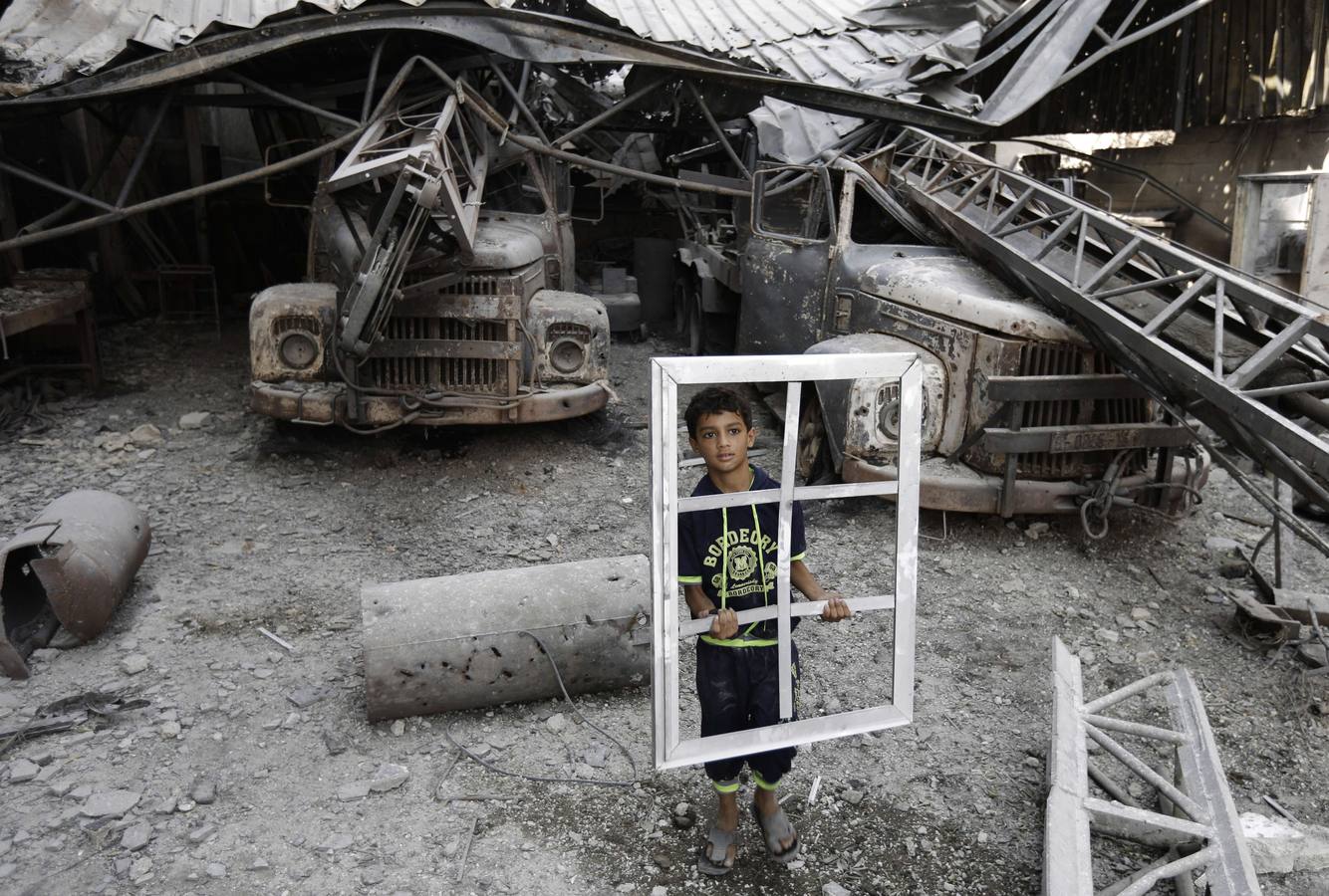 Un joven palestino sostiene un marco de la ventana mientras inspecciona un edificio destruido en el barrio de Al-Shejaea de la ciudad de Gaza.