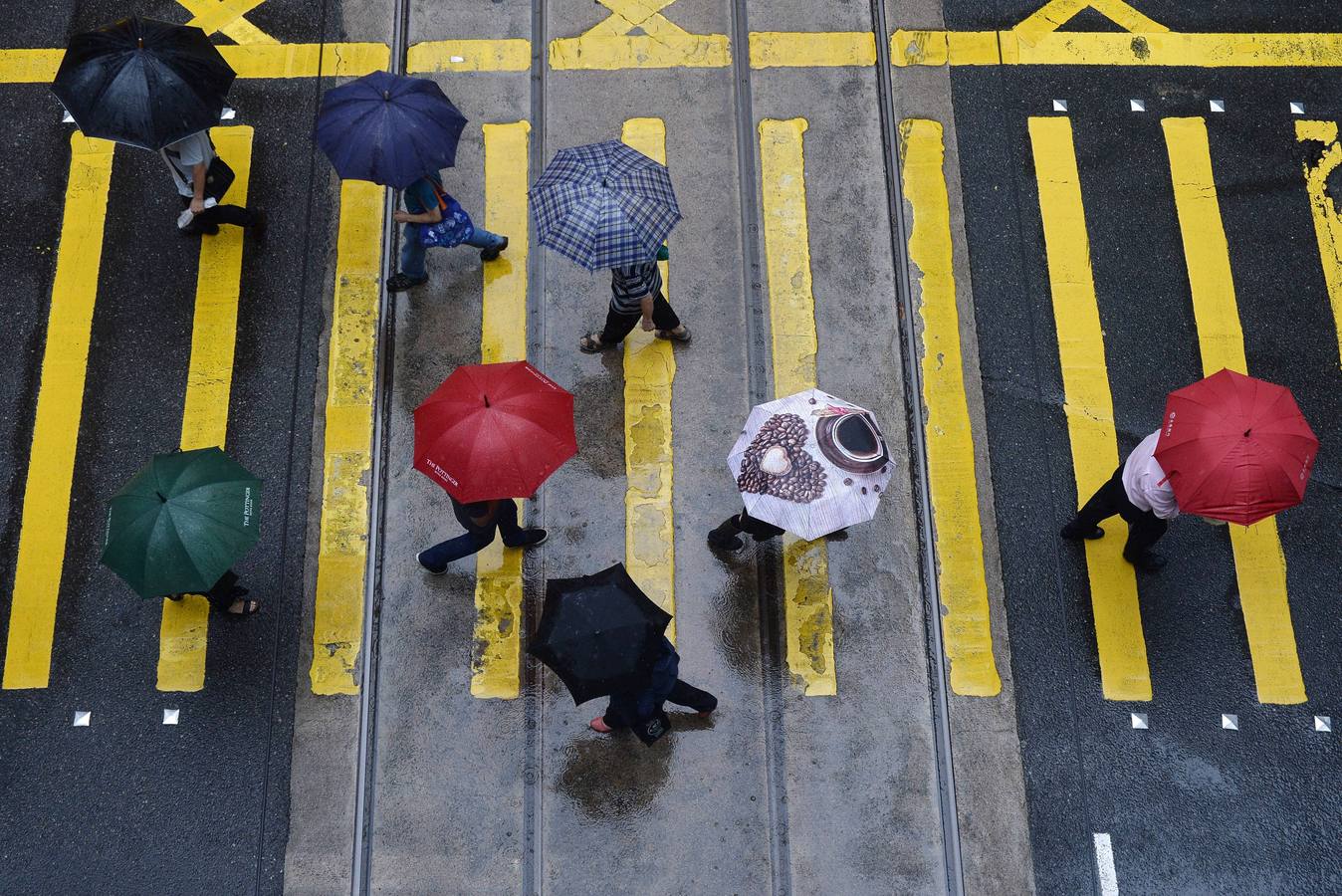 Personas se protegen de la lluvia con paraguas mientras cruzan una intersección en Hong Kong.