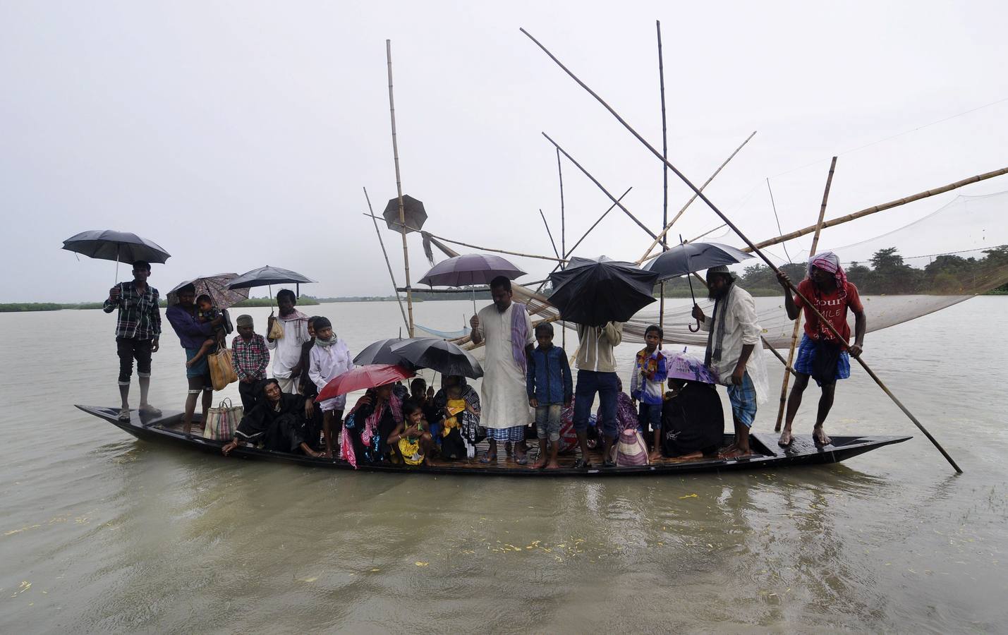 Los aldeanos indios salen de la orilla para viajar en barco a través de las inundaciones en la aldea Gagalmar.