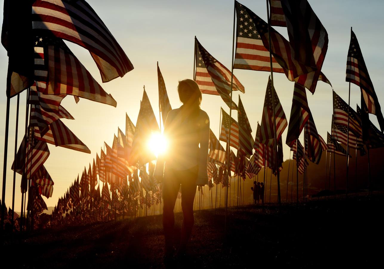 Una mujer camina entre las banderas de Estados Unidos levantadas por los estudiantes y de la Universidad de Pepperdine en honor a las víctimas de los 11 de septiembre de 2001 en Malibu, California.