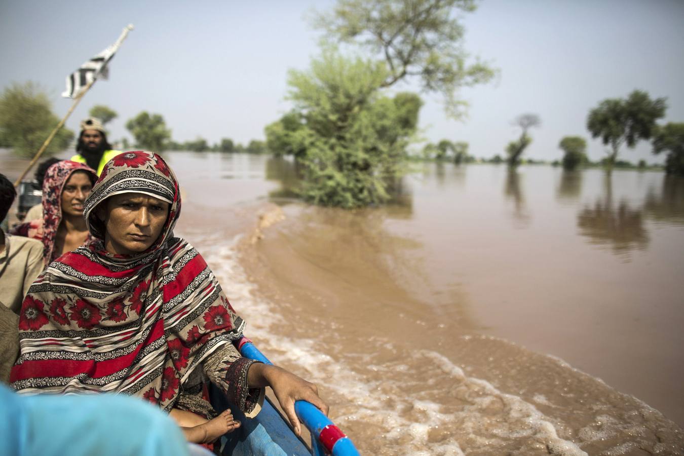 Una víctima de las inundaciones se sienta en un barco mientras eran evacuados de su casa inundada después de fuertes lluvias en Jhang, provincia de Punjab.