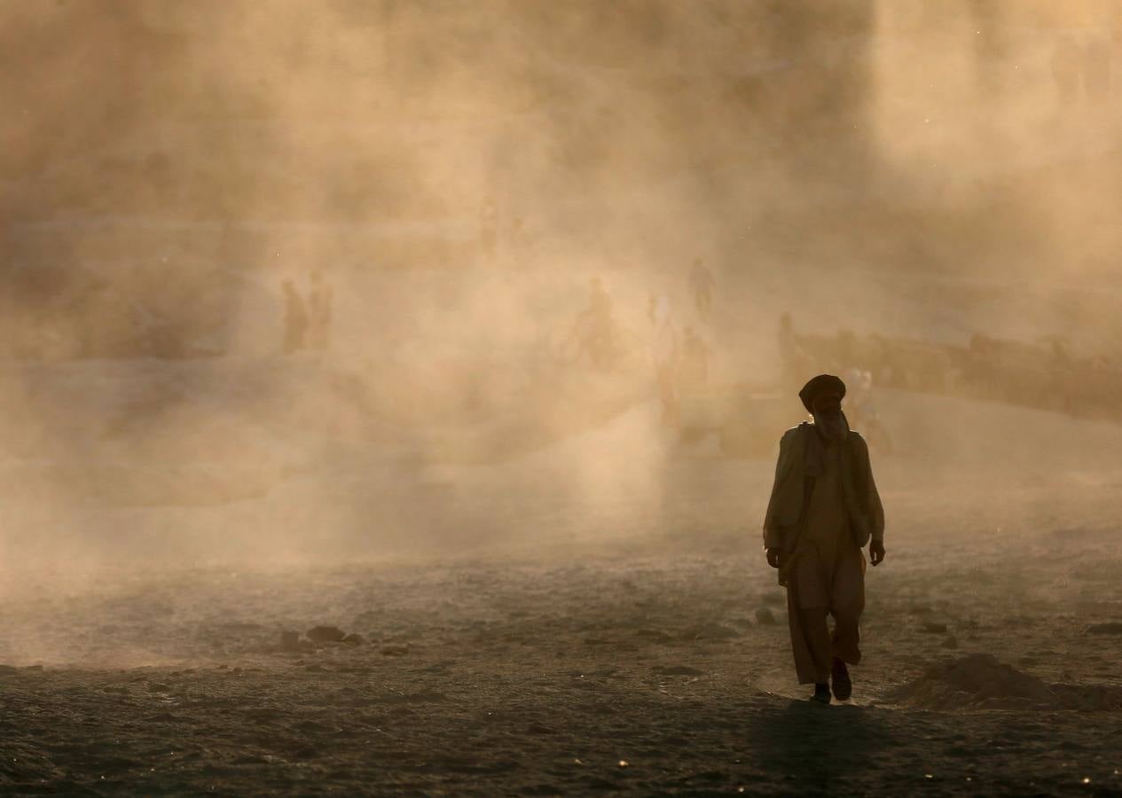 Un hombre afgano camina en medio de una nube de polvo en Kabul.