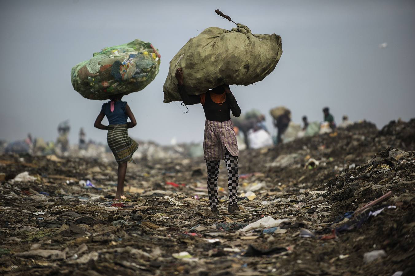 Niñas llevan bolsas con artículos de plástico y latas como recolectores de basura en el municipal Maputo vertido sitio en Maputo.